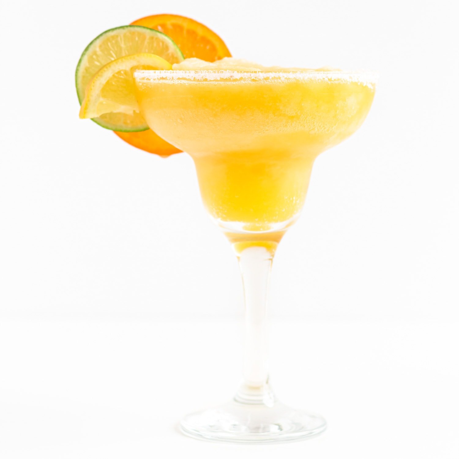 Single frozen citrus margarita garnished with orange, lemon and lime slices on a white background.