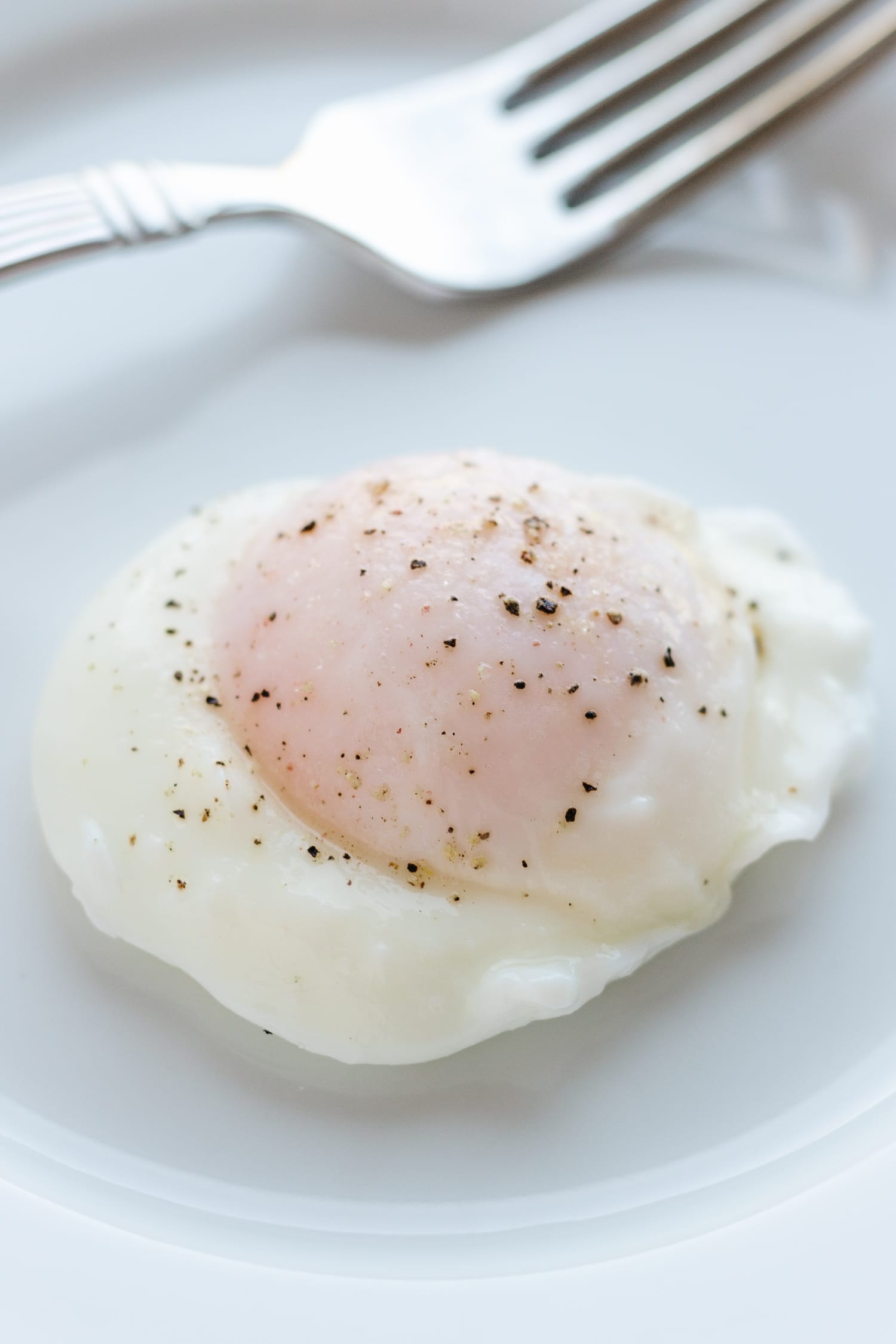 A poached egg with a fork on a white plate.