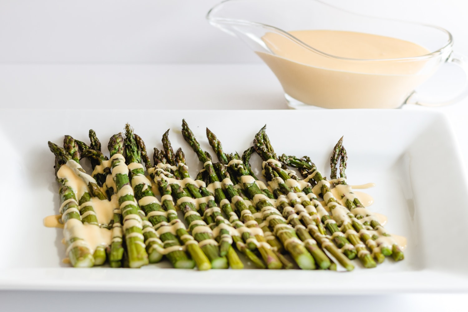 aspargus on a white platter with hollandaise sauce