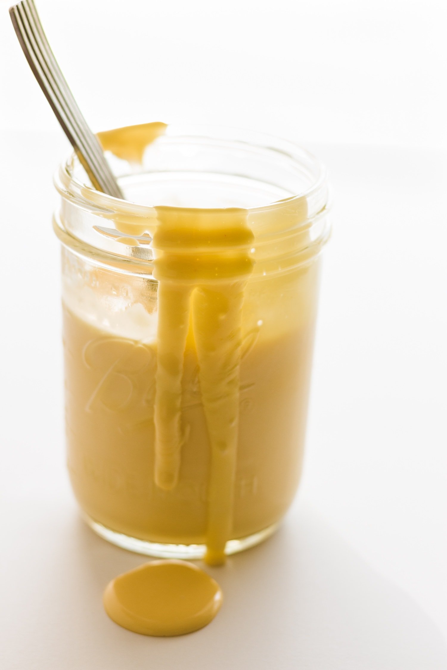 Hollandaise sauce in a mason jar , dripping down the front with spoon sticking out, 