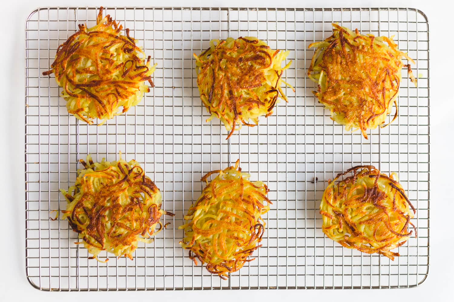 Overhead shot of 6 rosti on a metal cooling rack