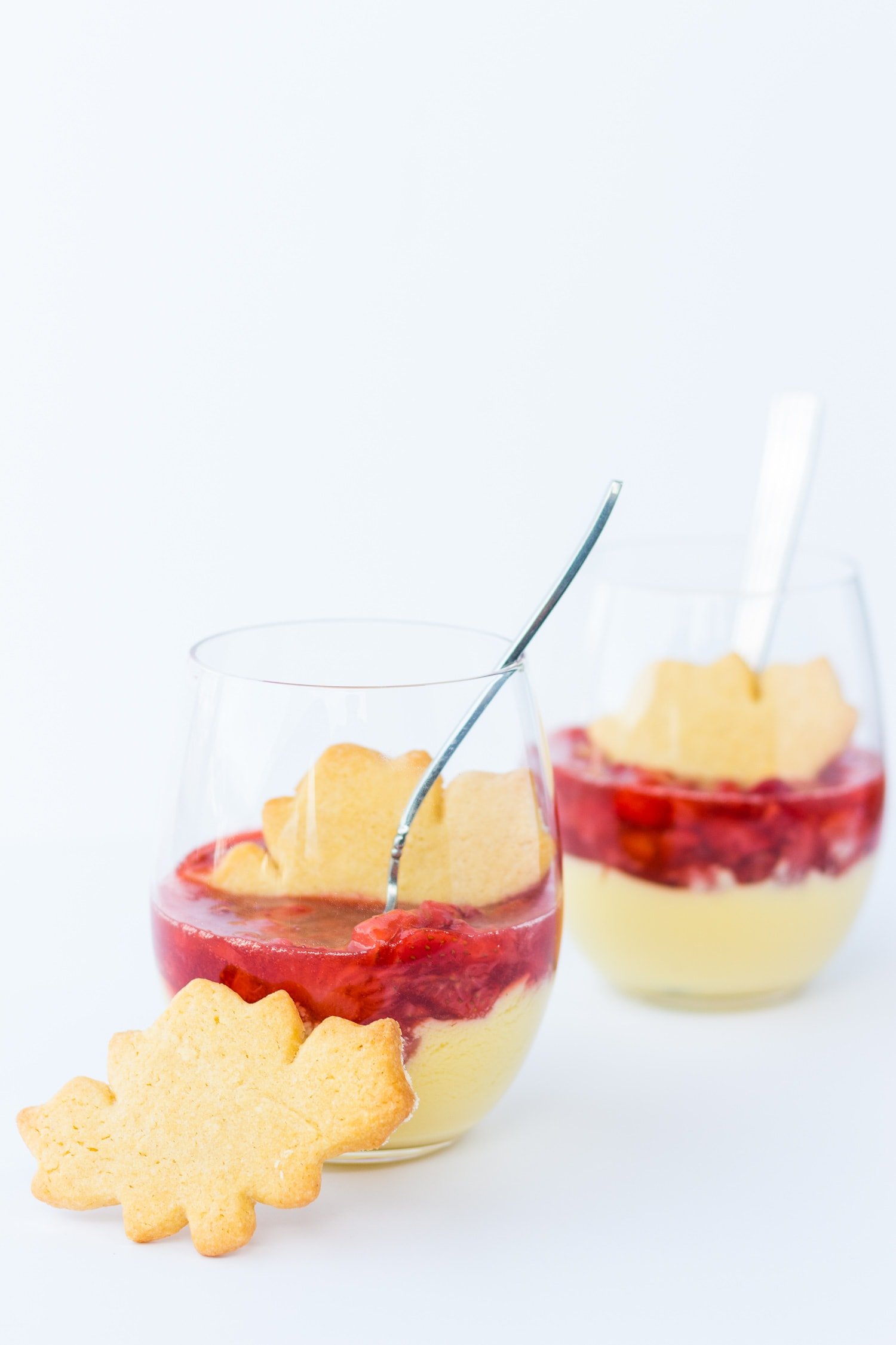 Two glasses of maple custard with strawberry compote with maple leaf shaped sugar cookies.