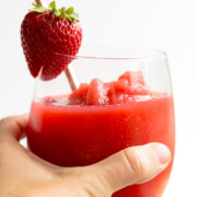 Hand holding glass of strawberry frose.