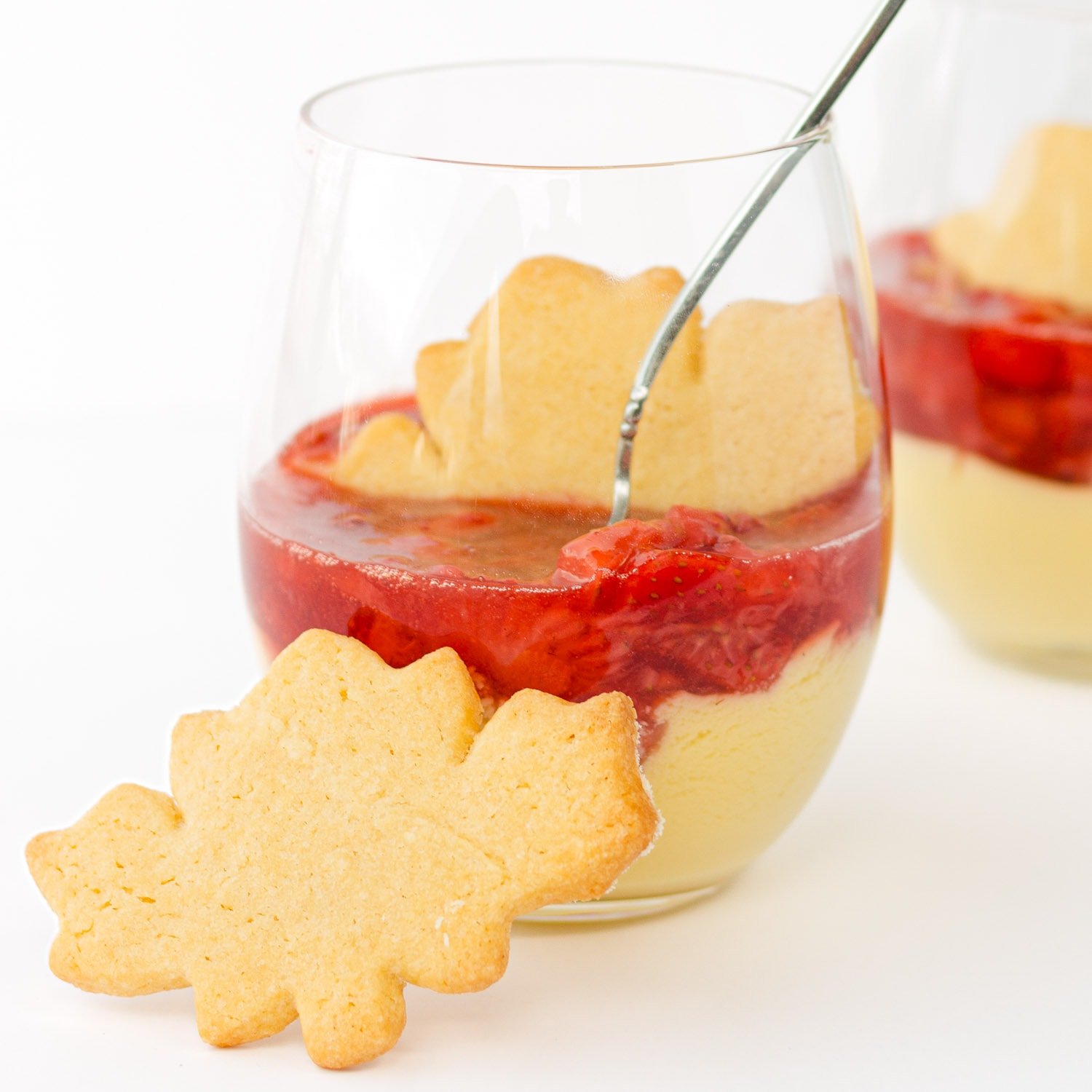 Maple custard with strawberry compote in a dessert glass with maple leaf shaped sugar cookie.