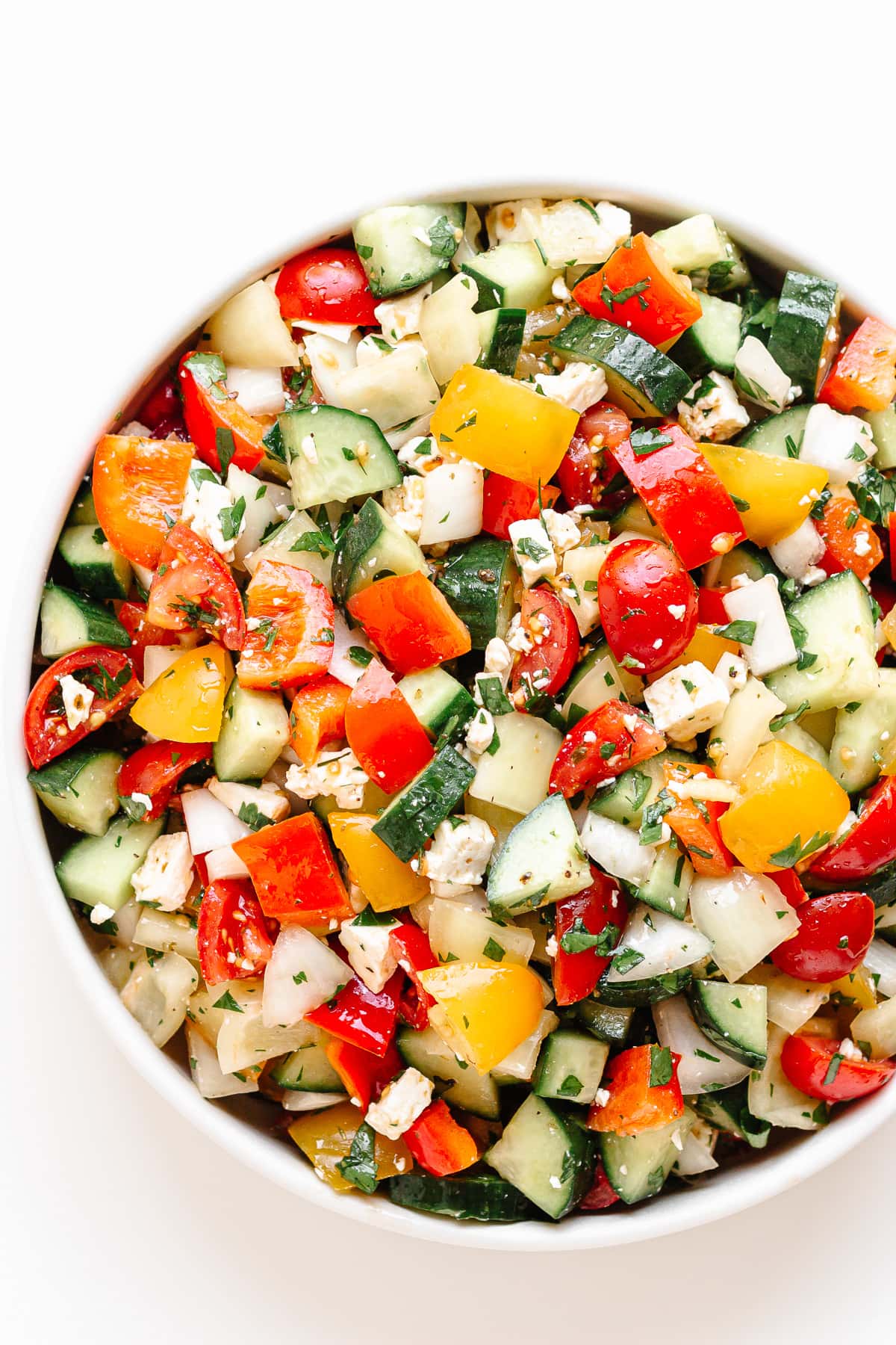 Close up of a bowl of summer chopped salad on a white background.