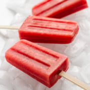 Watermelon Strawberry Popsicles sitting on ice.
