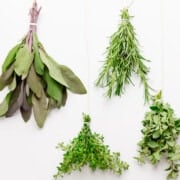 Four bundles of fresh herbs tied with kitchen twine.