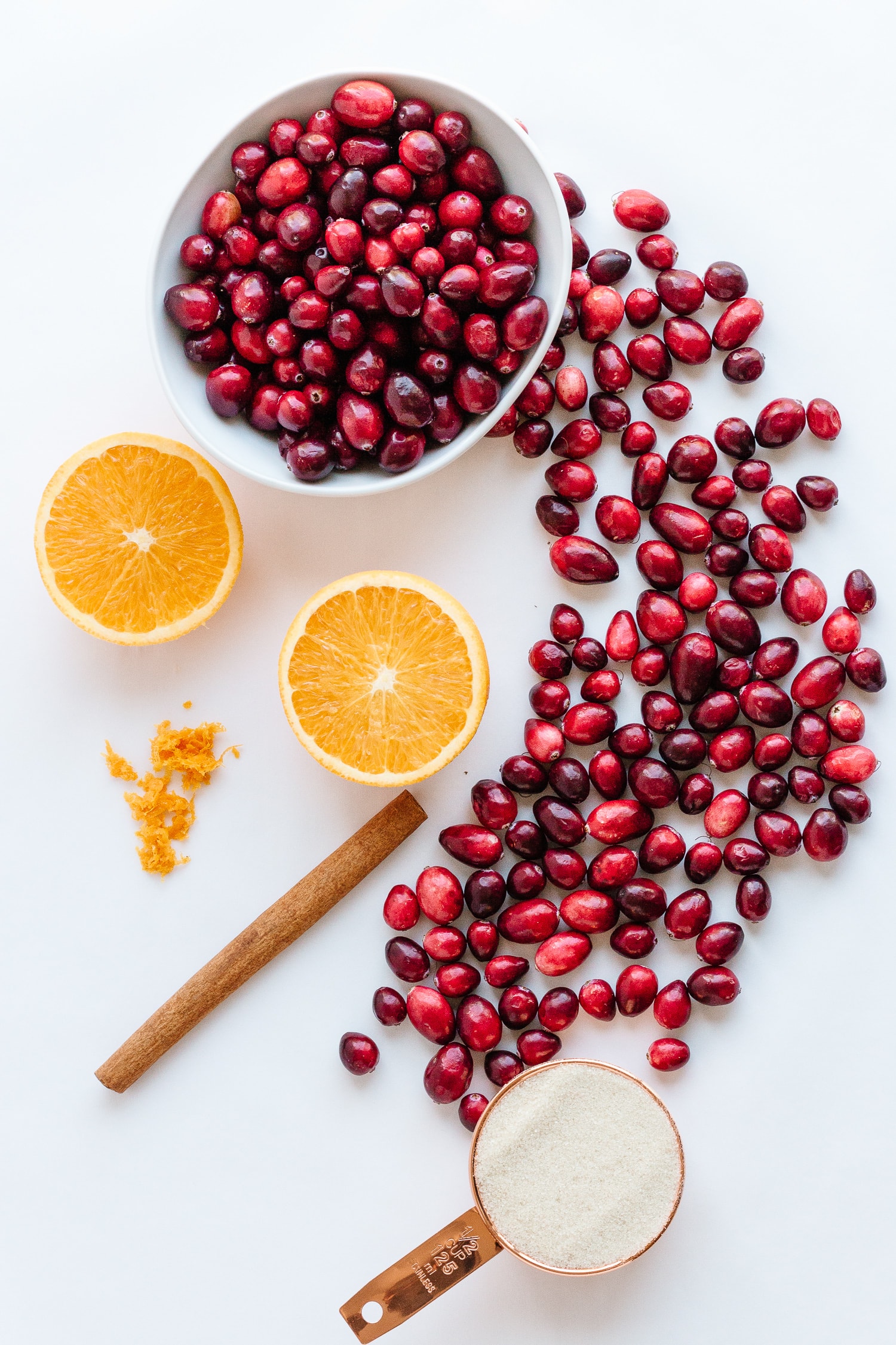 Overhead photo of ingredients needed to make the Cranberry Orange Sauce Recipe (cranberries, orange, cinnamon and sugar)