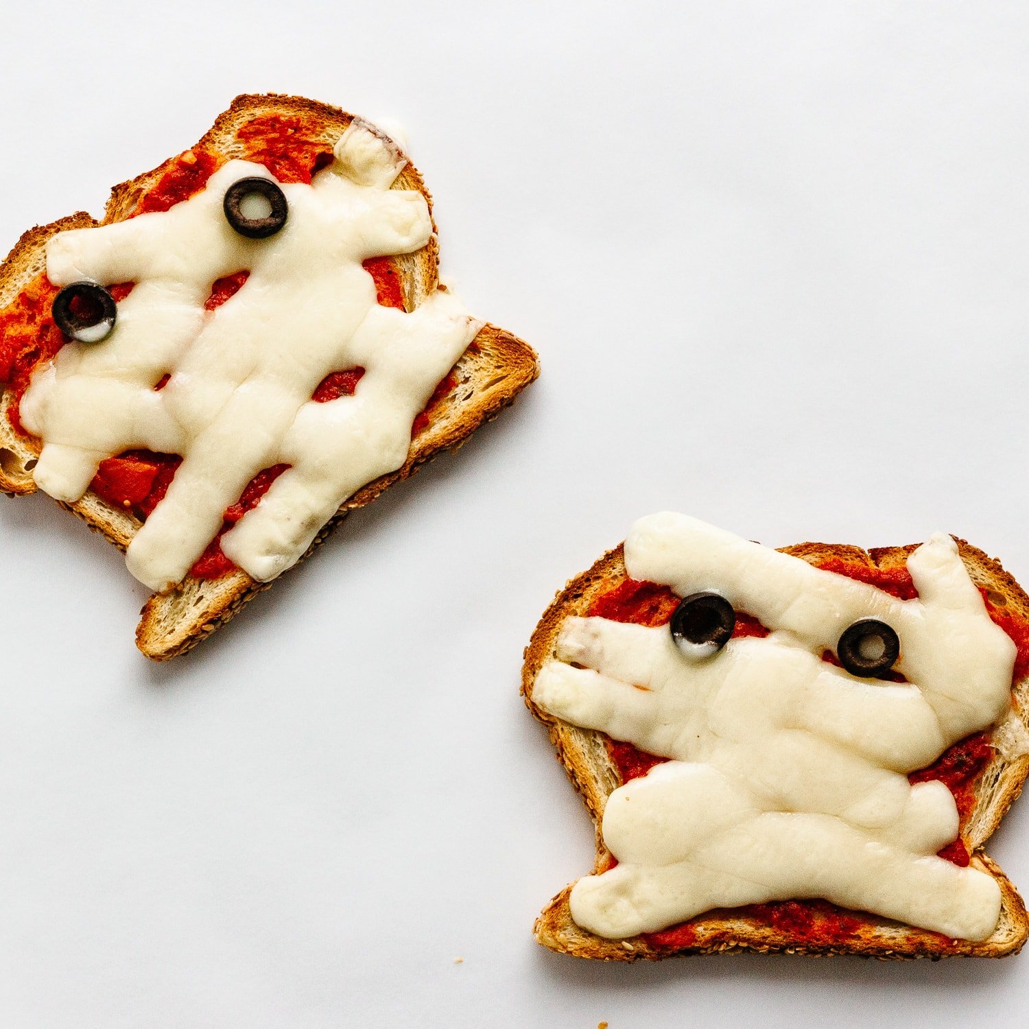 Pizza toast with strips of mozzarella and 2 black olive slices to look like a Halloween Mummy.