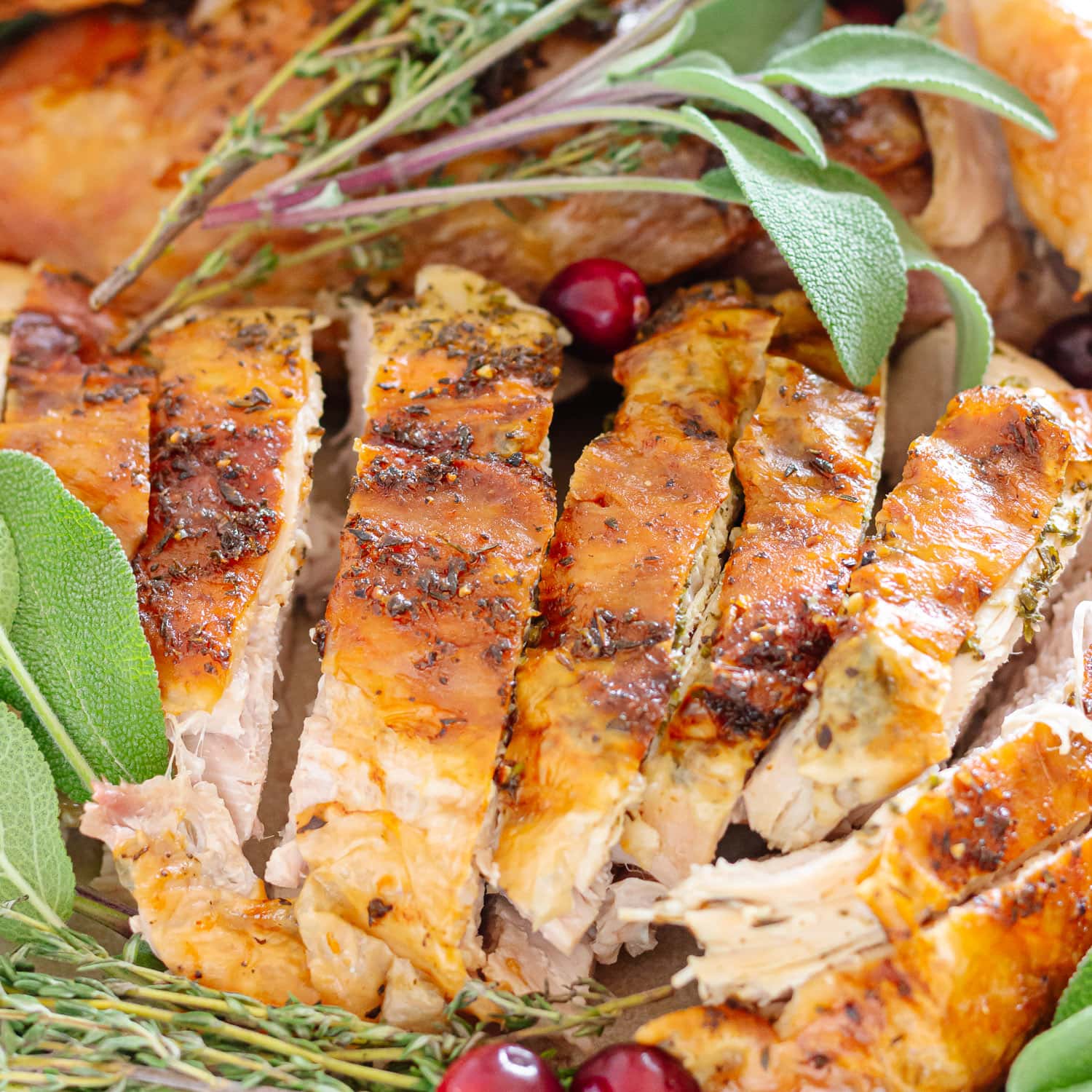 Closeup of some carved spatchcock herb butter turkey on a platter.