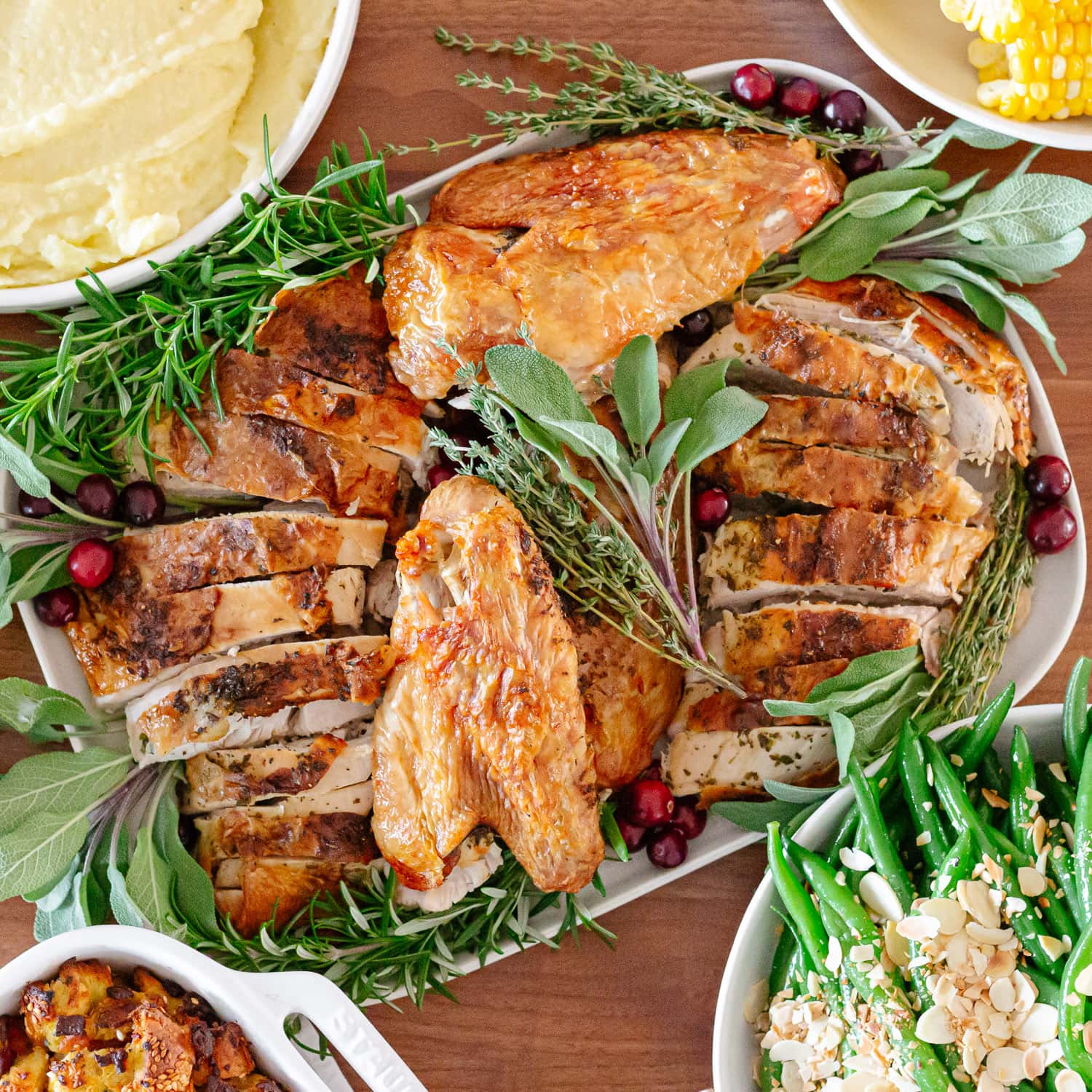 Carved turkey on a platter surrounded by side dishes.