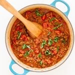 Bolognese sauce in a dutch oven with a wooden spoon.