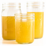 Three mason jars of turkey bone broth displayed on a white background.