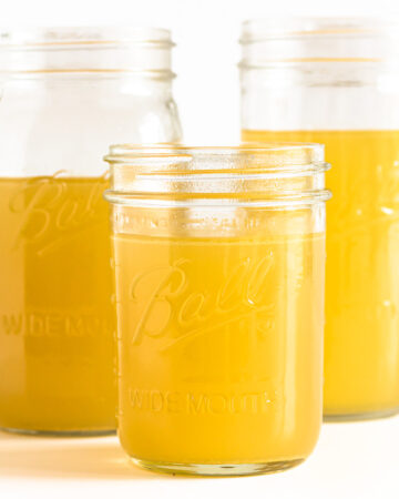 Three mason jars of turkey bone broth displayed on a white background.