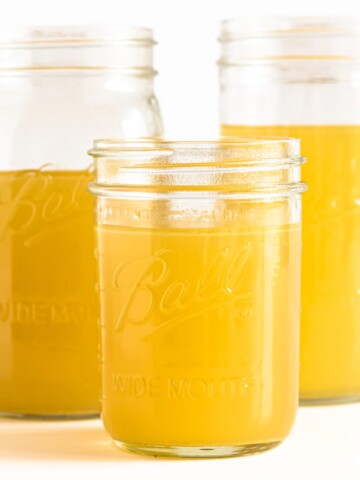 Three mason jars of turkey bone broth displayed on a white background.