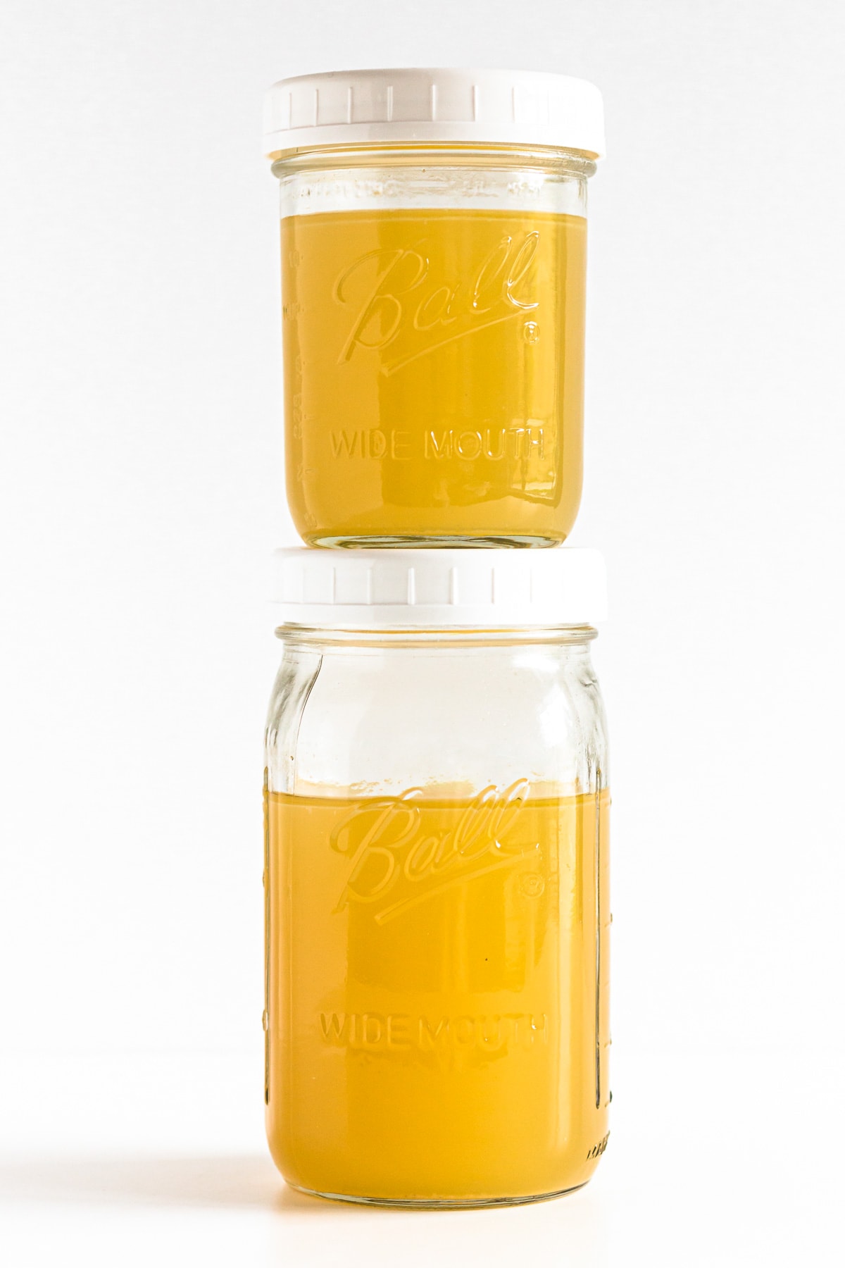 Two mason jars of turkey stock stacked on top of each other.