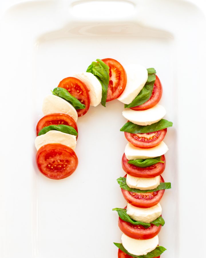 Caprese Salad arranged in the shape of a candy cane on a white platter