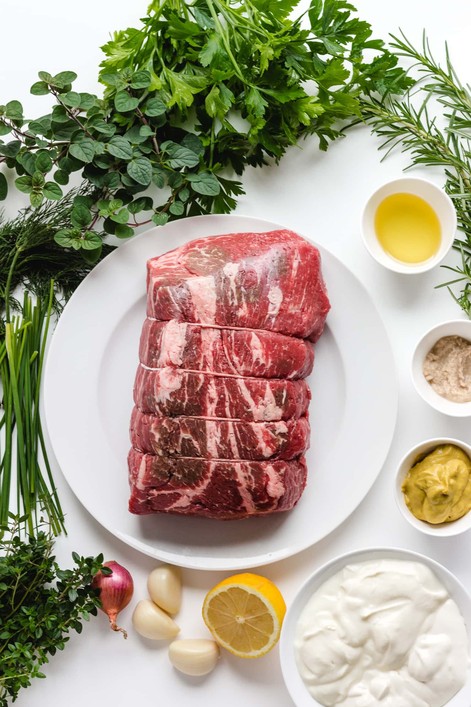 Overhead photo on a white background of all the ingredients needed to make Herb Mustard Crusted Roast Beef with Creamy Herb Sauce.