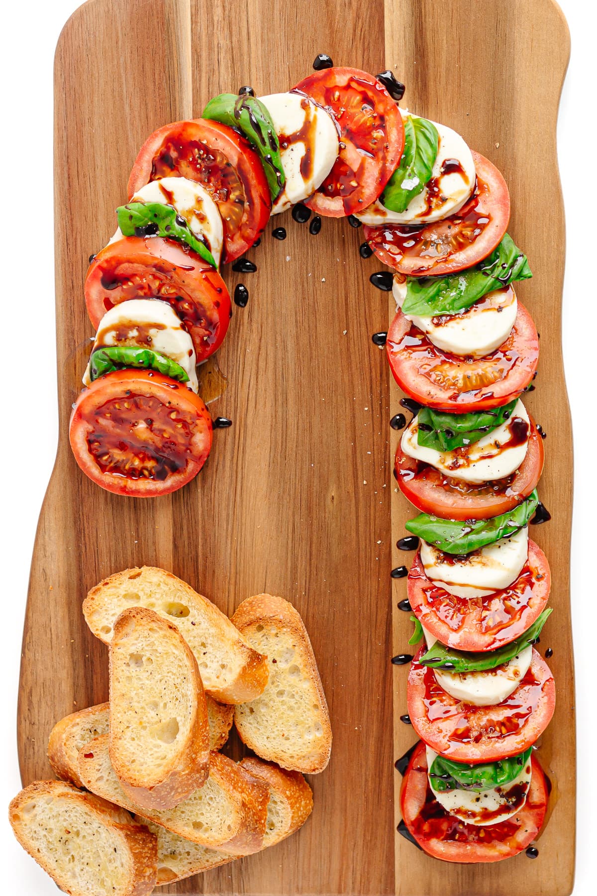Candy cane caprese with crostini on a wooden board.