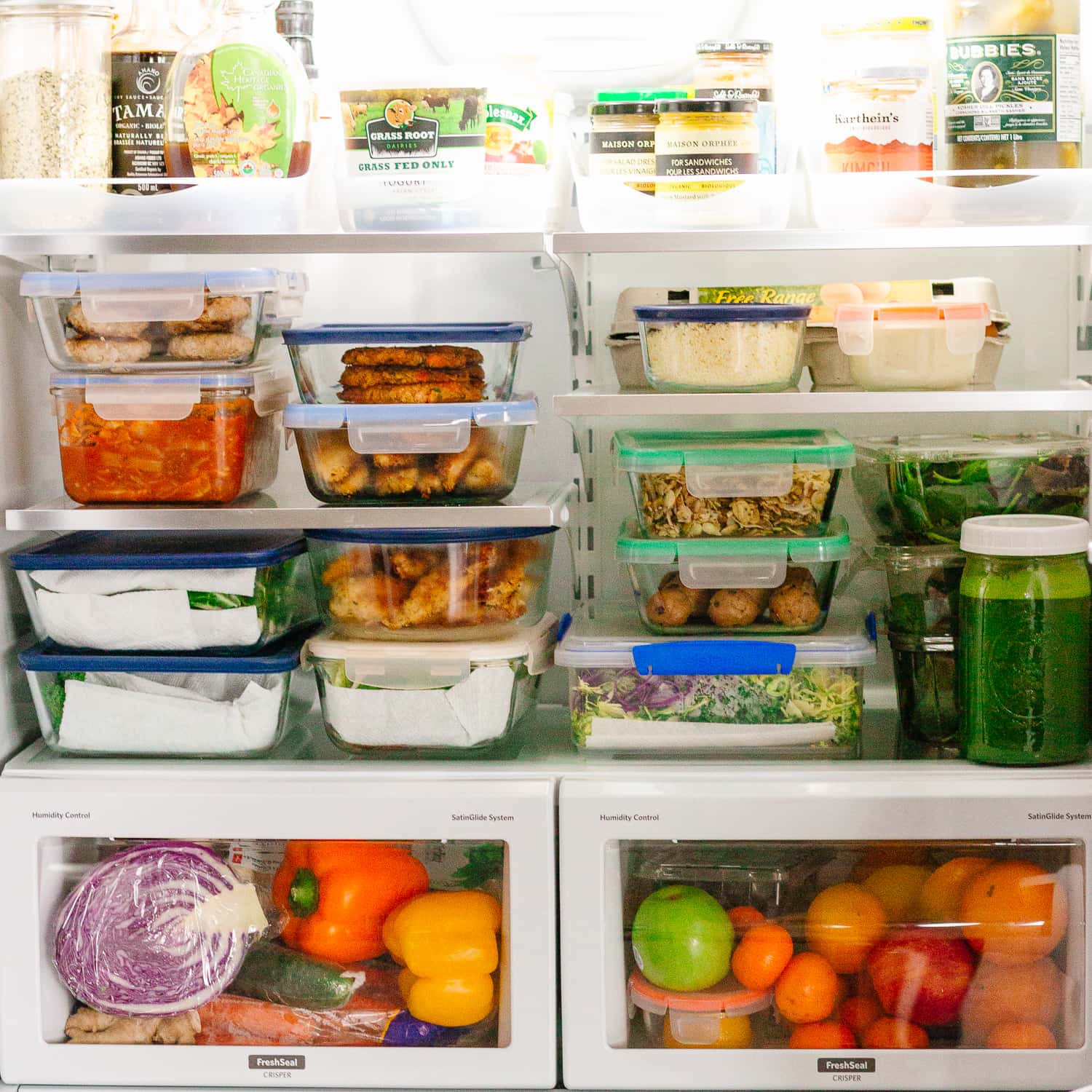 Inside of a fridge filled with containers of meal prep recipes made from The HealthNut Cookbook