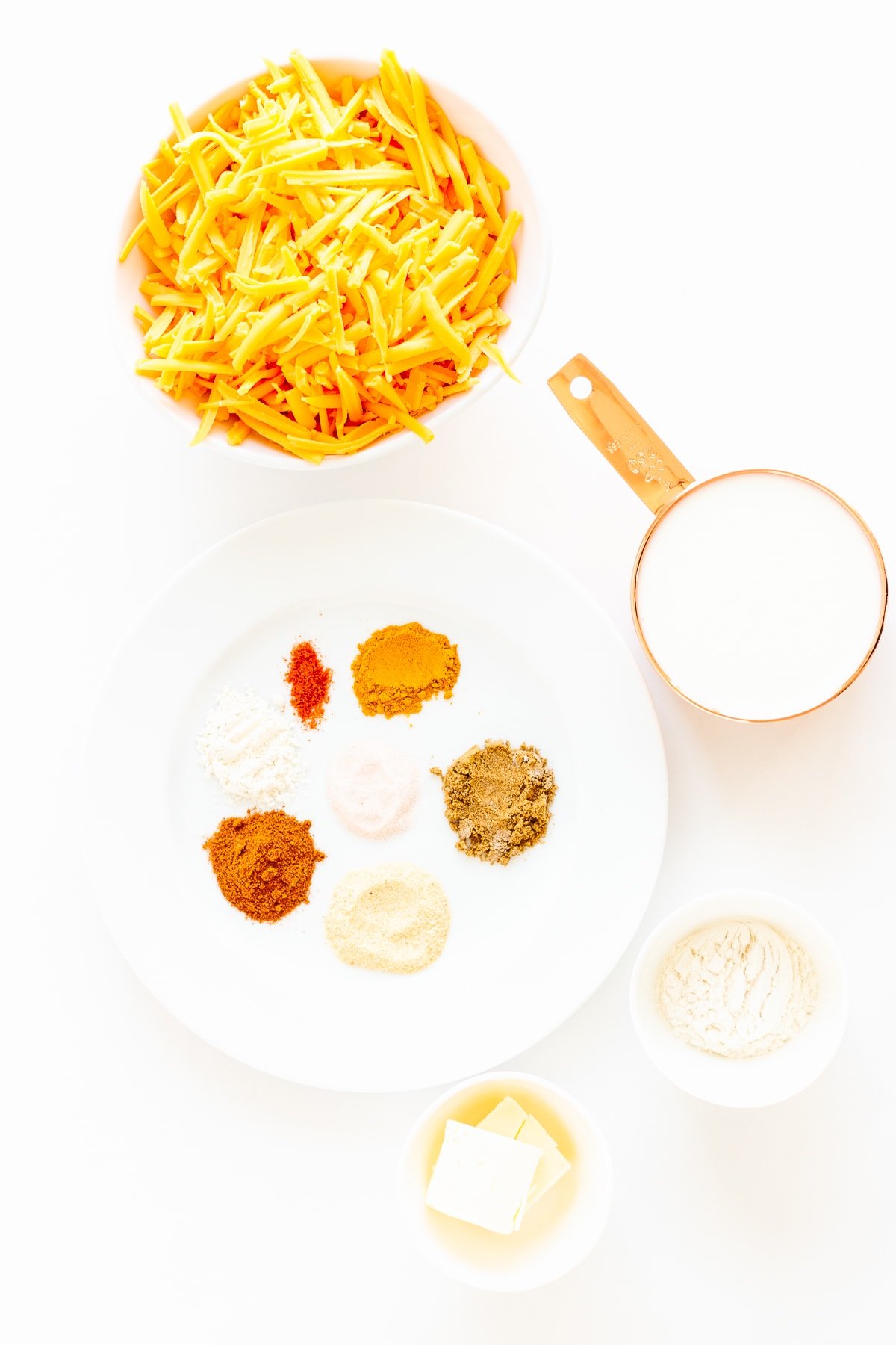 All the ingredients needed to make homemade nacho cheese sauce laid out on a white surface.