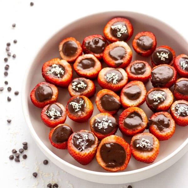 White bowl of chocolate coconut cream stuffed strawberries.