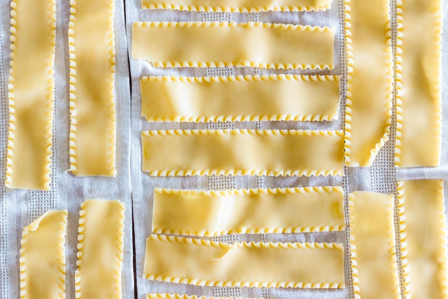 Cooked lasagna noodles laid out on dish towels.