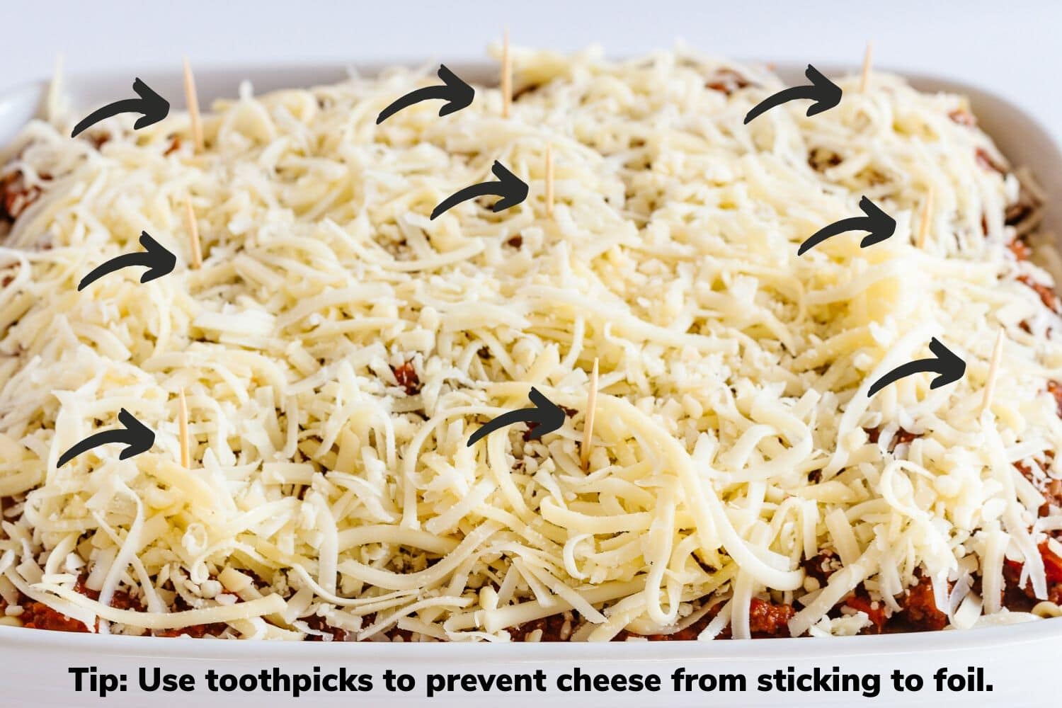 Photo diagram showing toothpicks placed in lasagna in order to prevent cheese from sticking to foil.