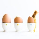 Three soft boiled eggs in egg cups.