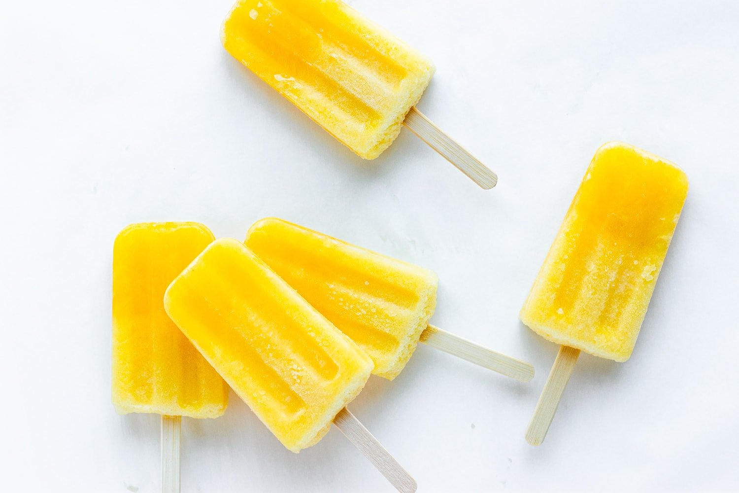 Five orange lemon lime popsicles displayed on a white background.