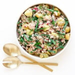 Overhead photo of a bowl of tuna potato salad with gold coloured salad servers next to it.