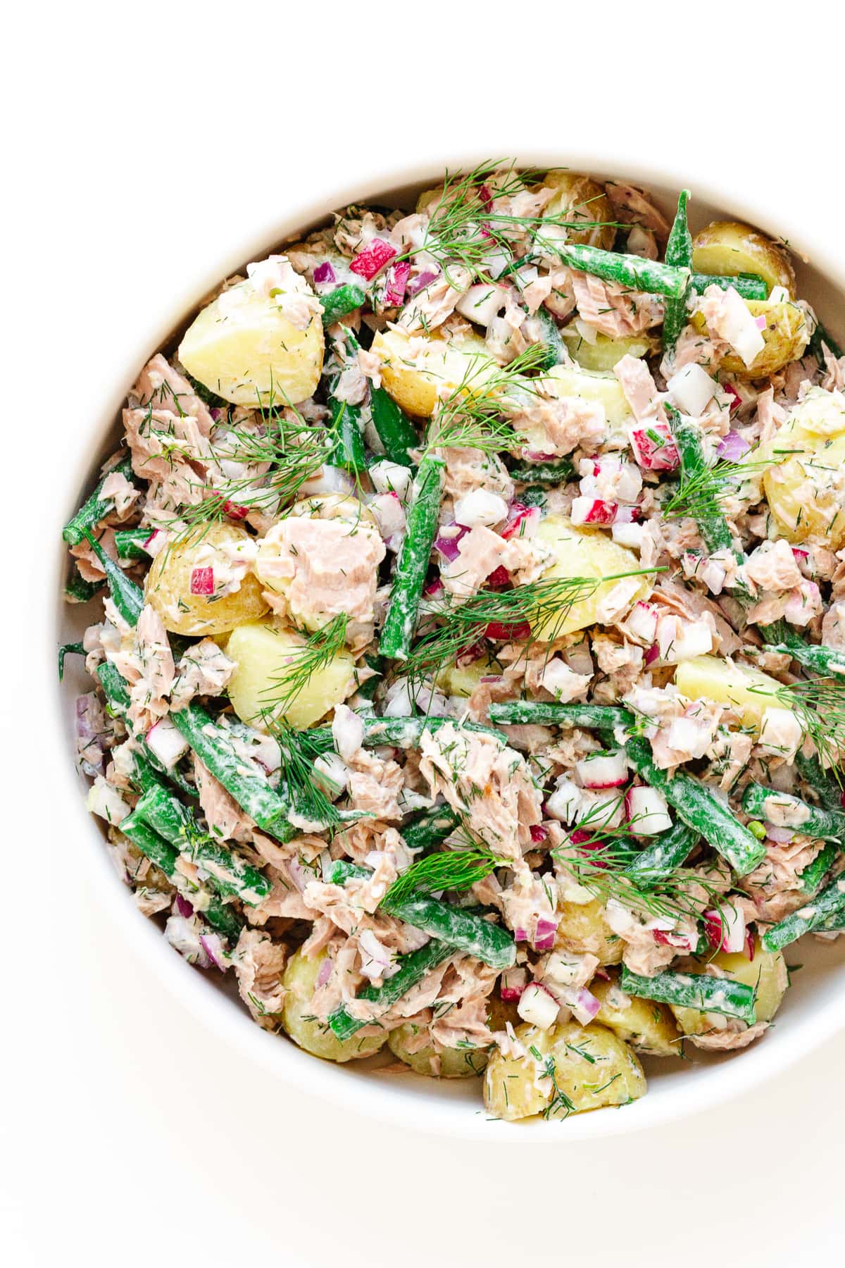 Close up overhead photo of tuna potato salad in a white bowl.
