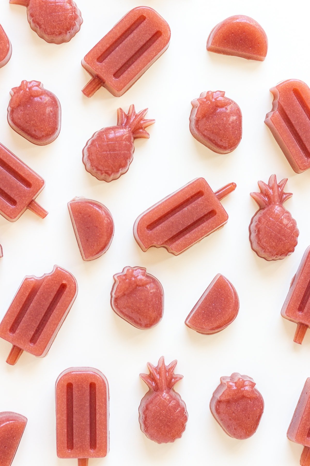 Variety of homemade strawberry gummies on a white background.