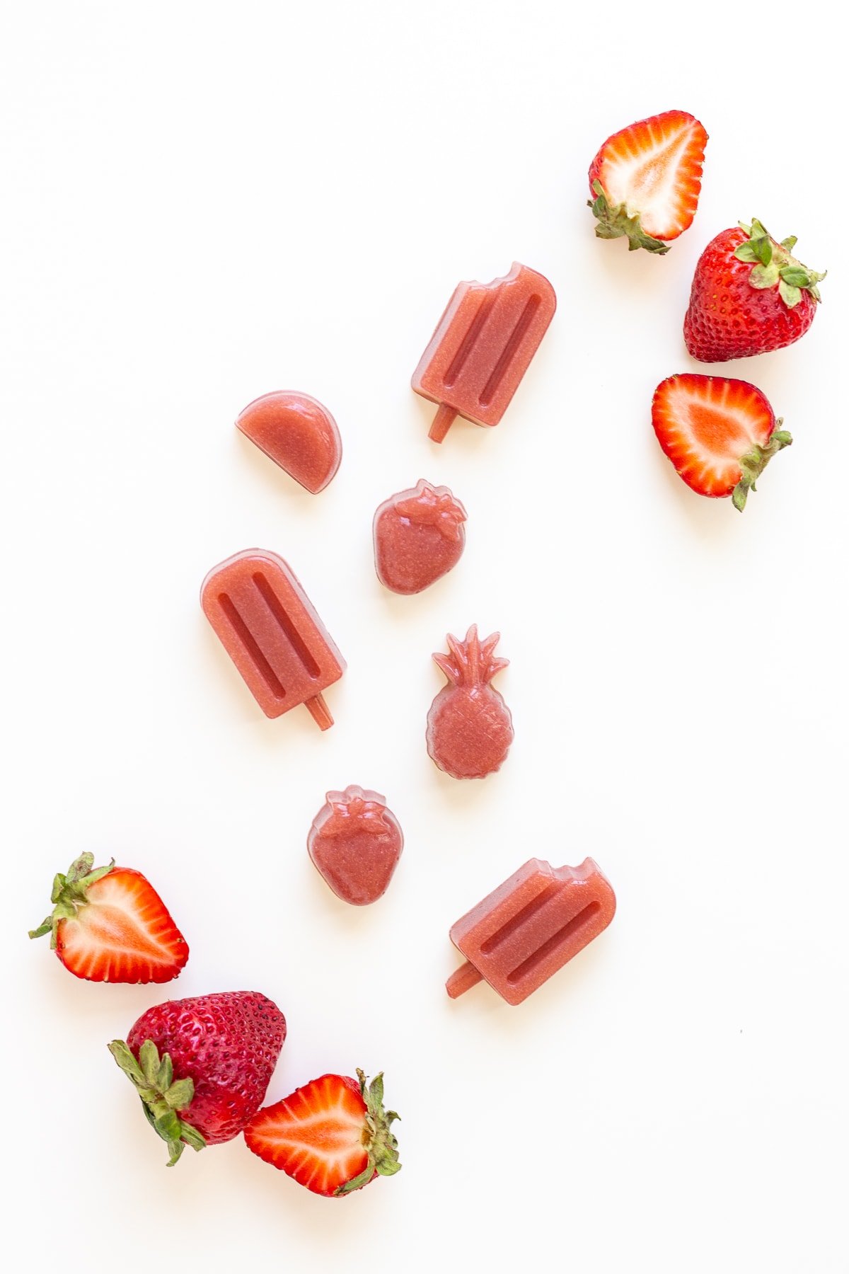 Strawberry gummies and fresh strawberries on a white background.