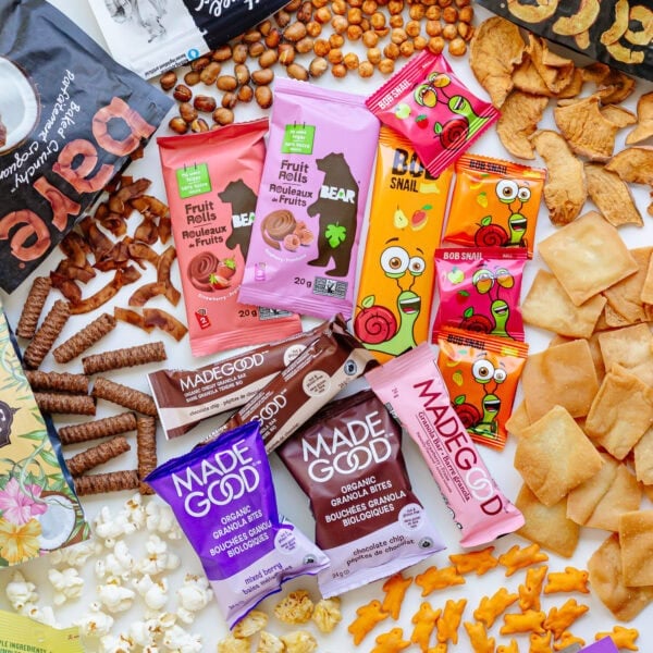 Variety of packaged snacks for kids spread out on a white surface.