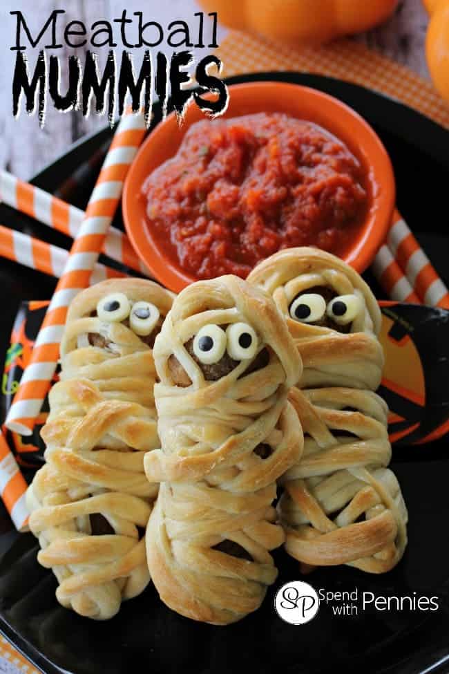 Three meatball mummies on a black plate.