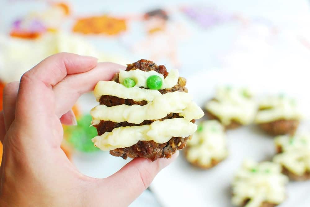 Hand holding a mini mummy meatloaf.