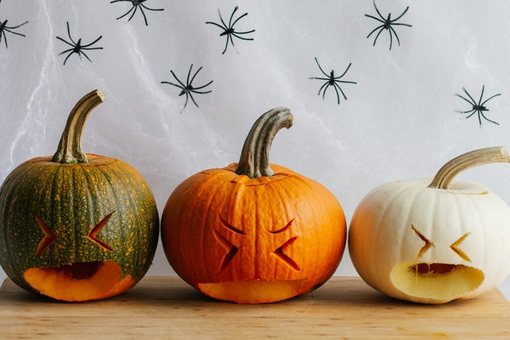 Three small carved pumpkins sitting on a wooden board.