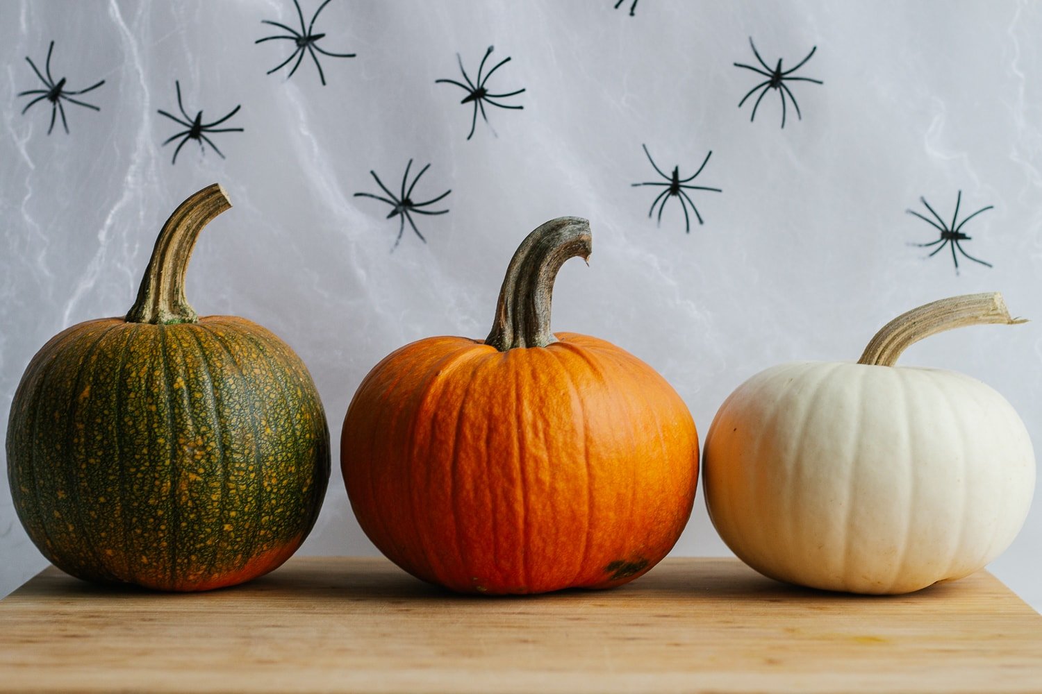 Three small pumpkins sitting on a wooden board.