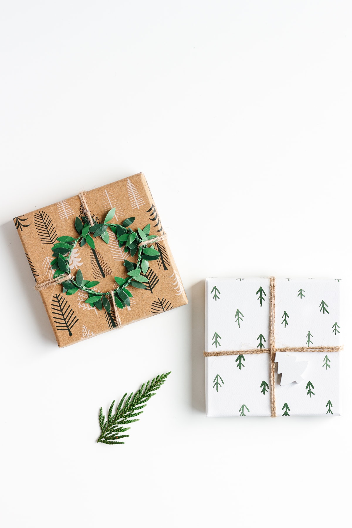 Overhead photo of two Christmas gifts and a small evergreen branch on a white background.