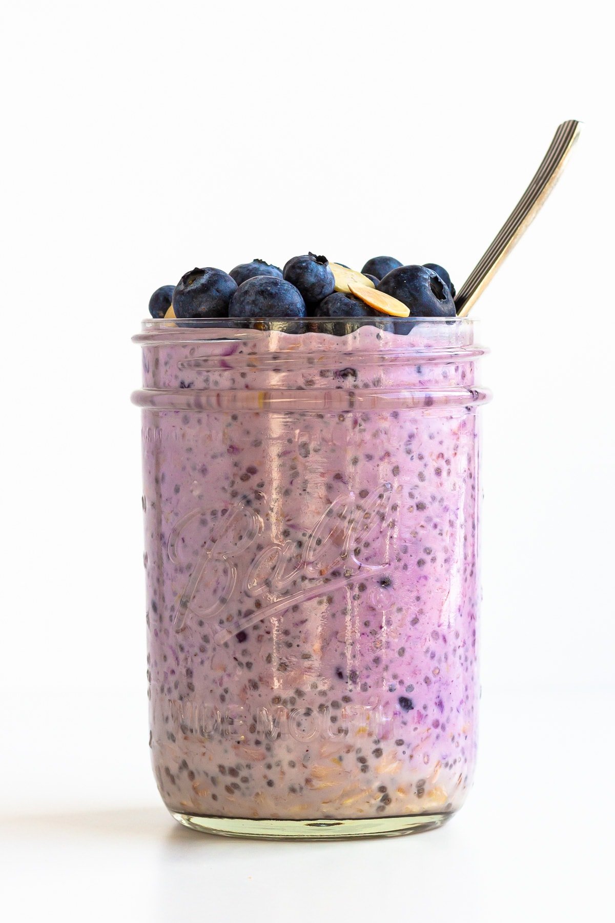 Mason jar of blueberry overnight oats with spoon.