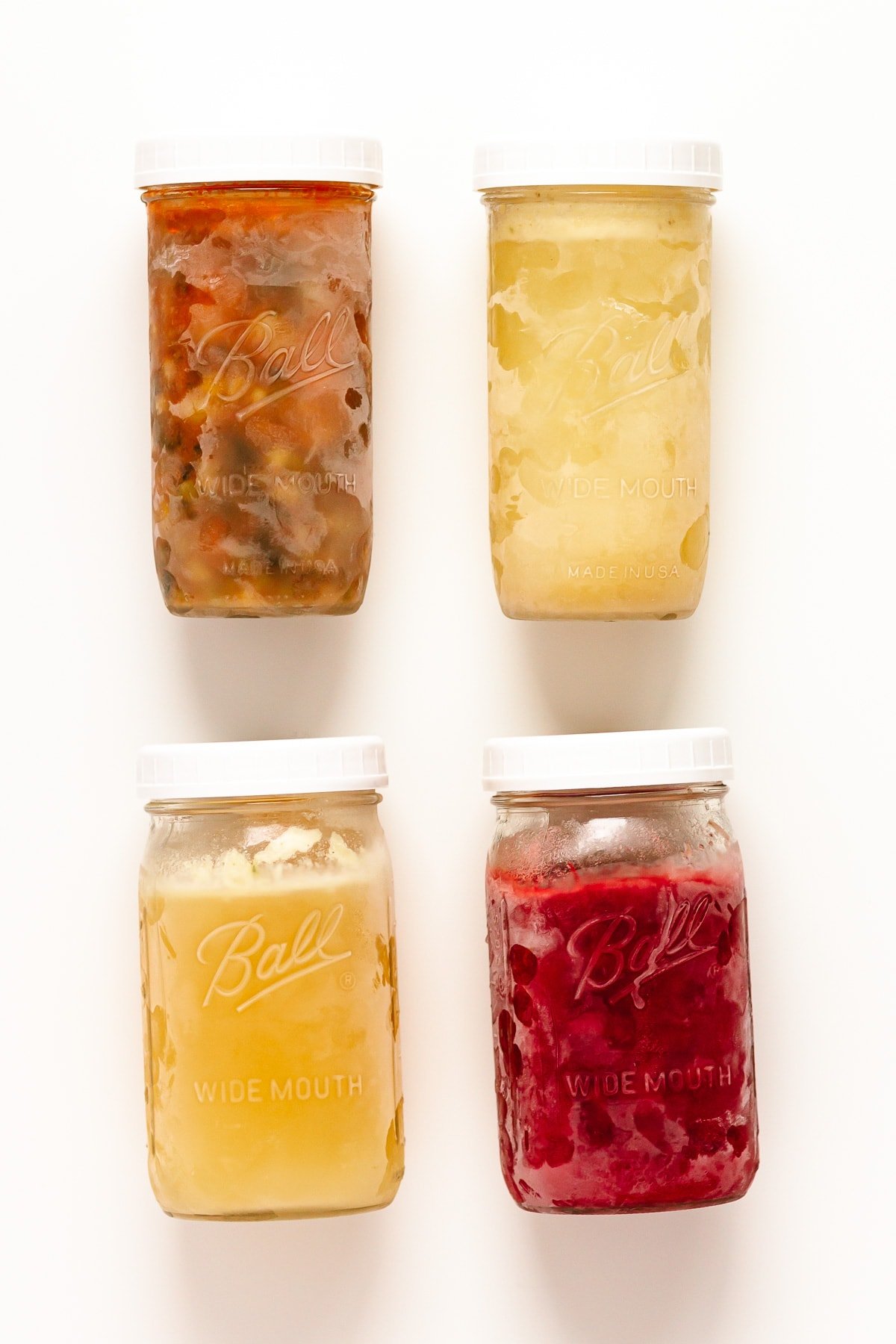 Four frozen mason jars containing different foods.