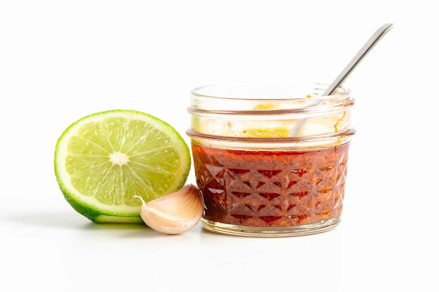 Small jar of fajita marinade with half a lime and a garlic clove next to it.