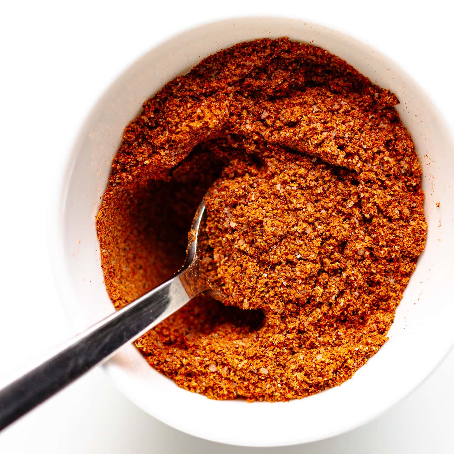 Fajita spice mix being stirred together with a spoon in a small white bowl.