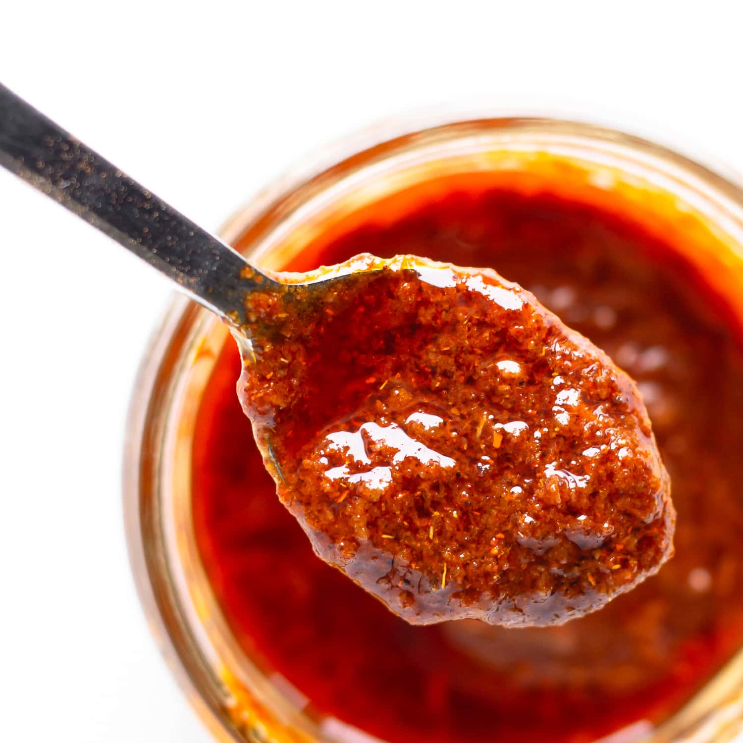 Spoon lifting fajita spice paste (marinade) out of a jar.