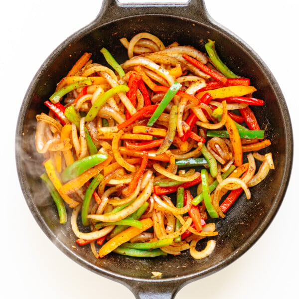 Fajita veggies sizzling in a cast iron skillet.