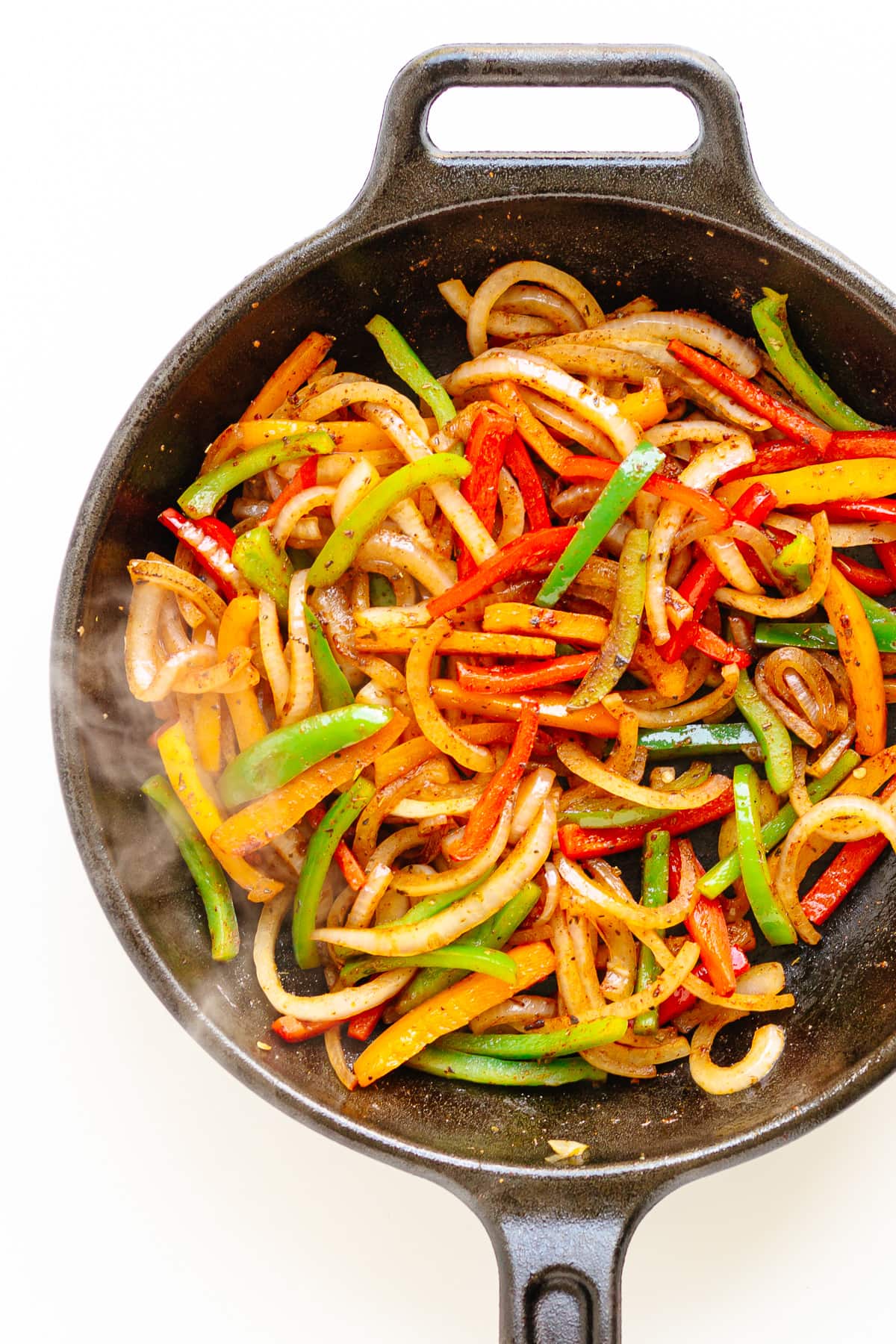 Fajita veggies sizzling in a cast iron skillet.