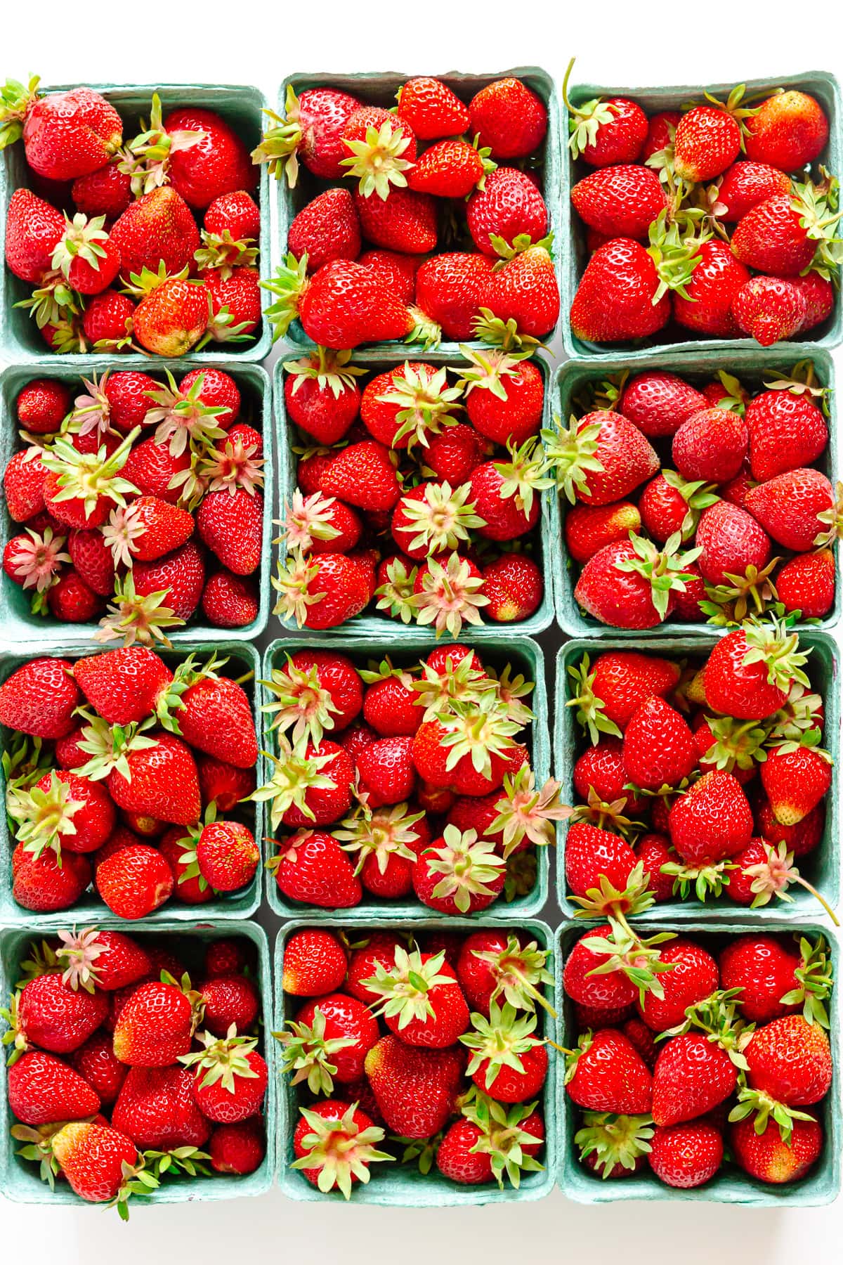 Overhead photo of twelve boxes of fresh strawberries.