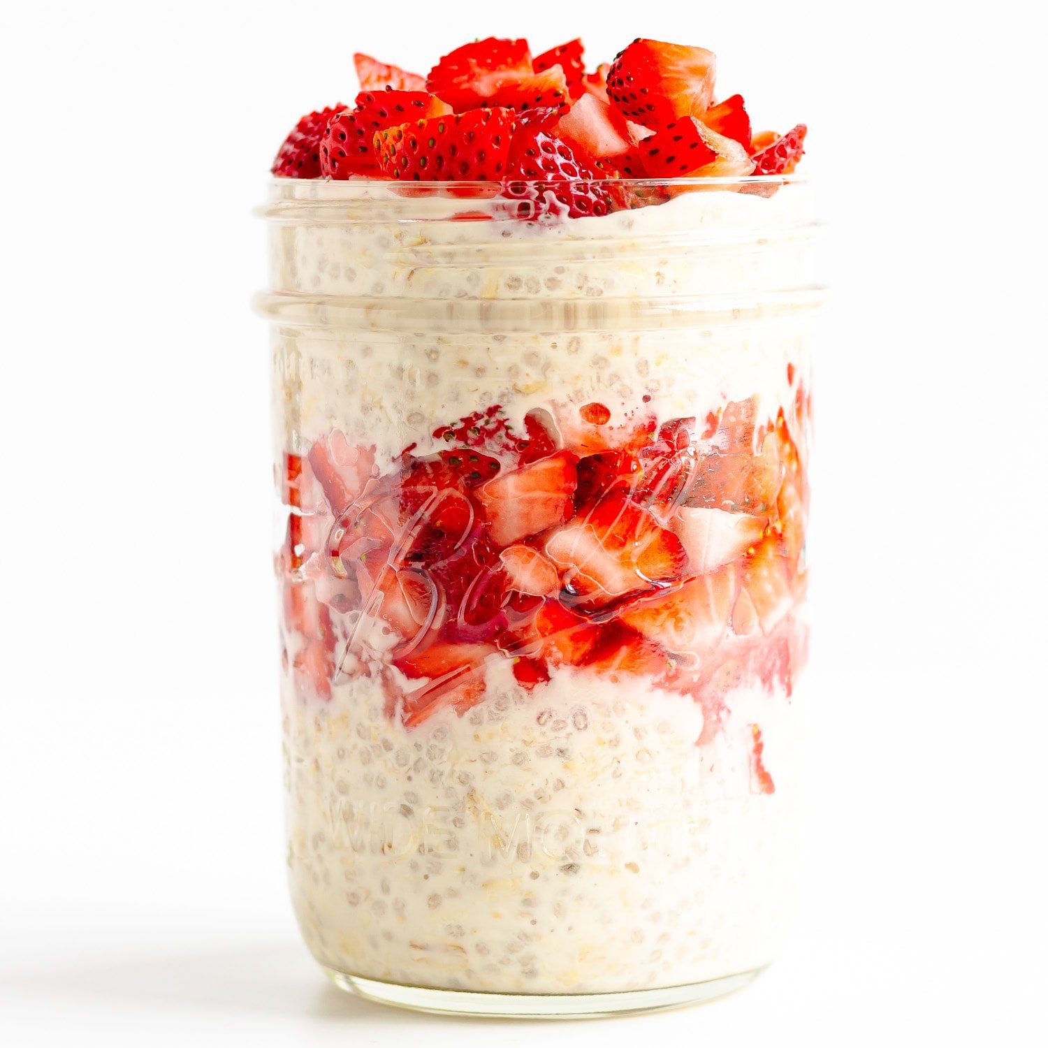 Mason jar filled with overnights oats and chopped strawberries in a layered pattern.