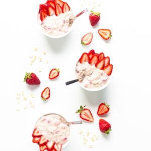 Overhead view of three bowls of strawberry overnight oats garnished with strawberry slices.